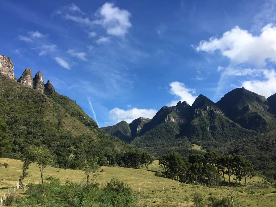 Os quatro paredões de pedra dos Soldados de Sebold, com montanhas verdes e céu azul