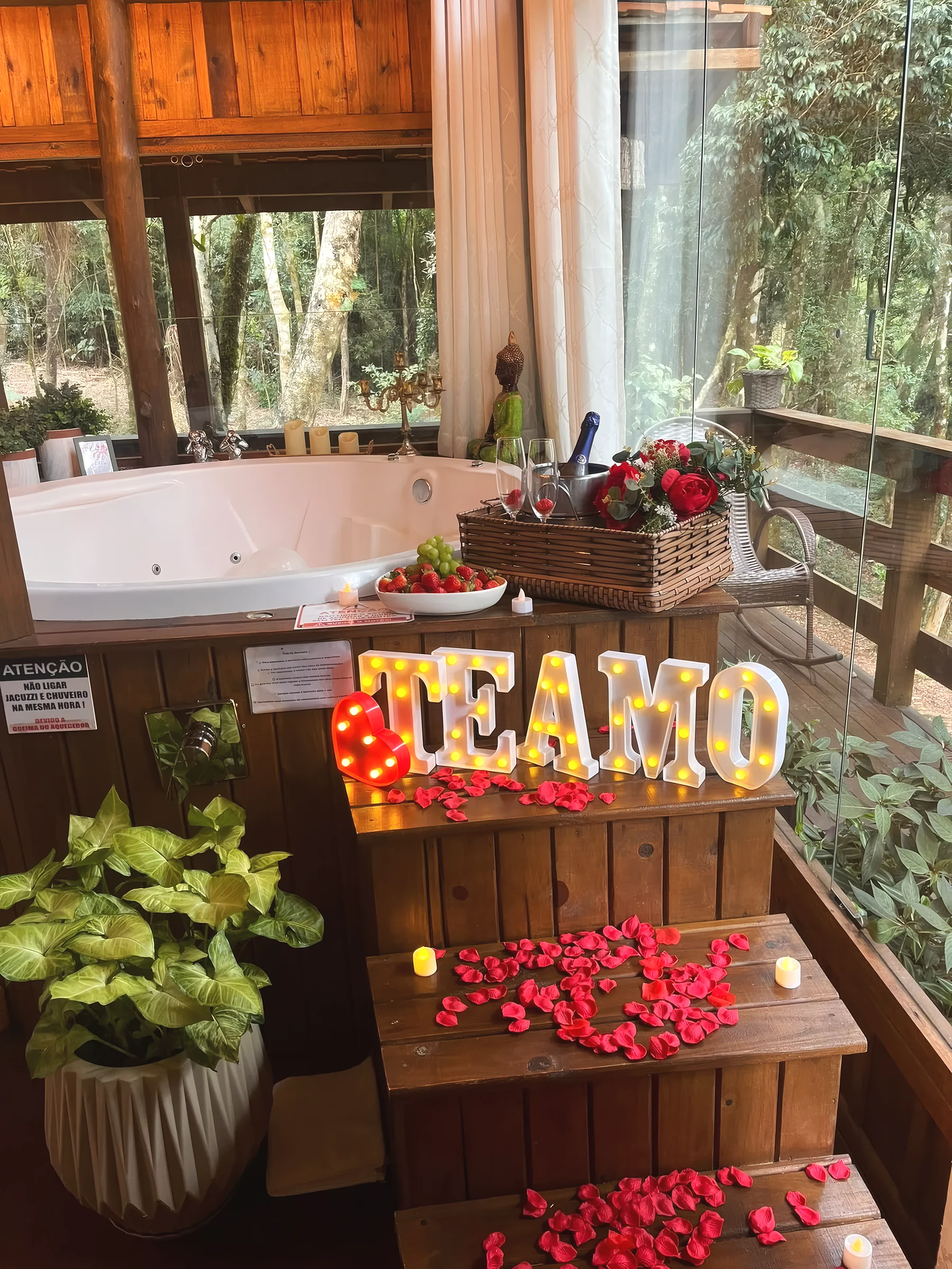 Escada da hidromassagem da Aurora decorada com letreiro Te amo, pétalas, velas e espumante