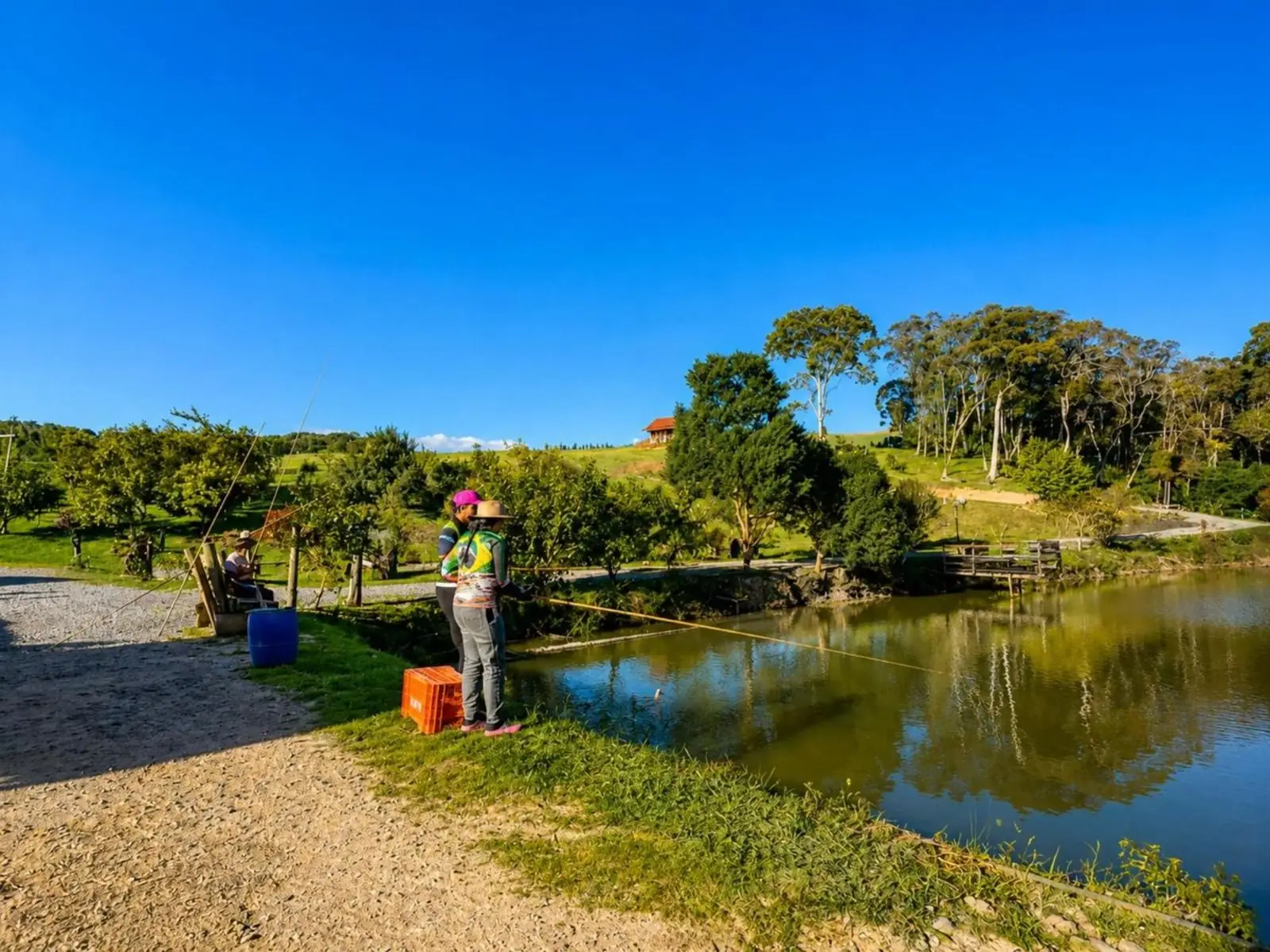 Hóspede pescando na beira do lago, num dia de céu azul