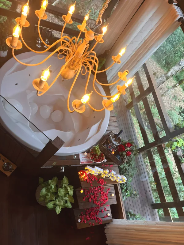 Banheira de hidromassagem vista de cima com balões, pétalas, velas, espumante e letreiro Te amo