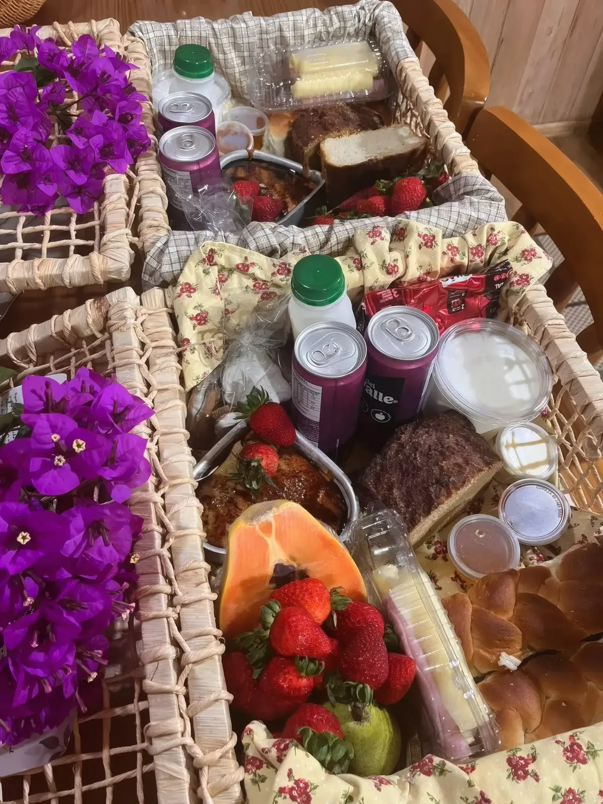 Cesta do café colonial com morangos, mamão, bolo, pães, iogurte e geleias