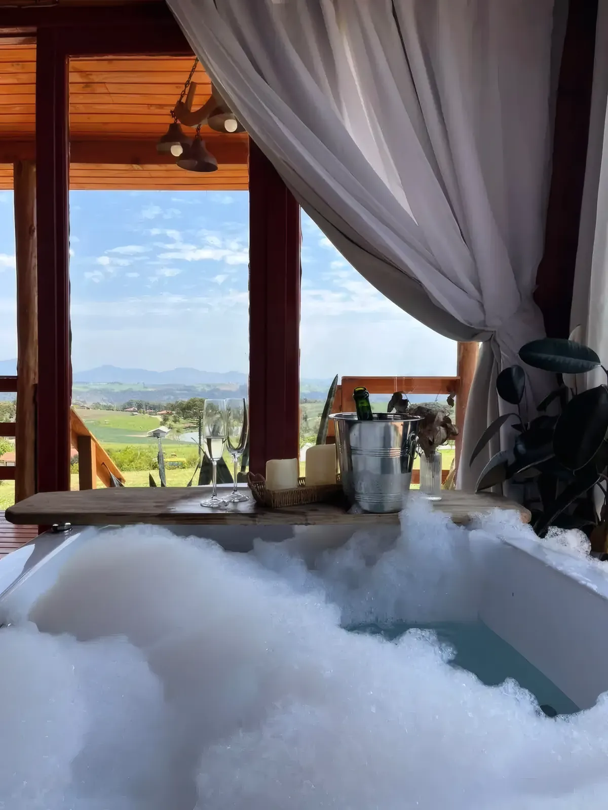 Banheira de hidromassagem com espuma e janela aberta para o campo